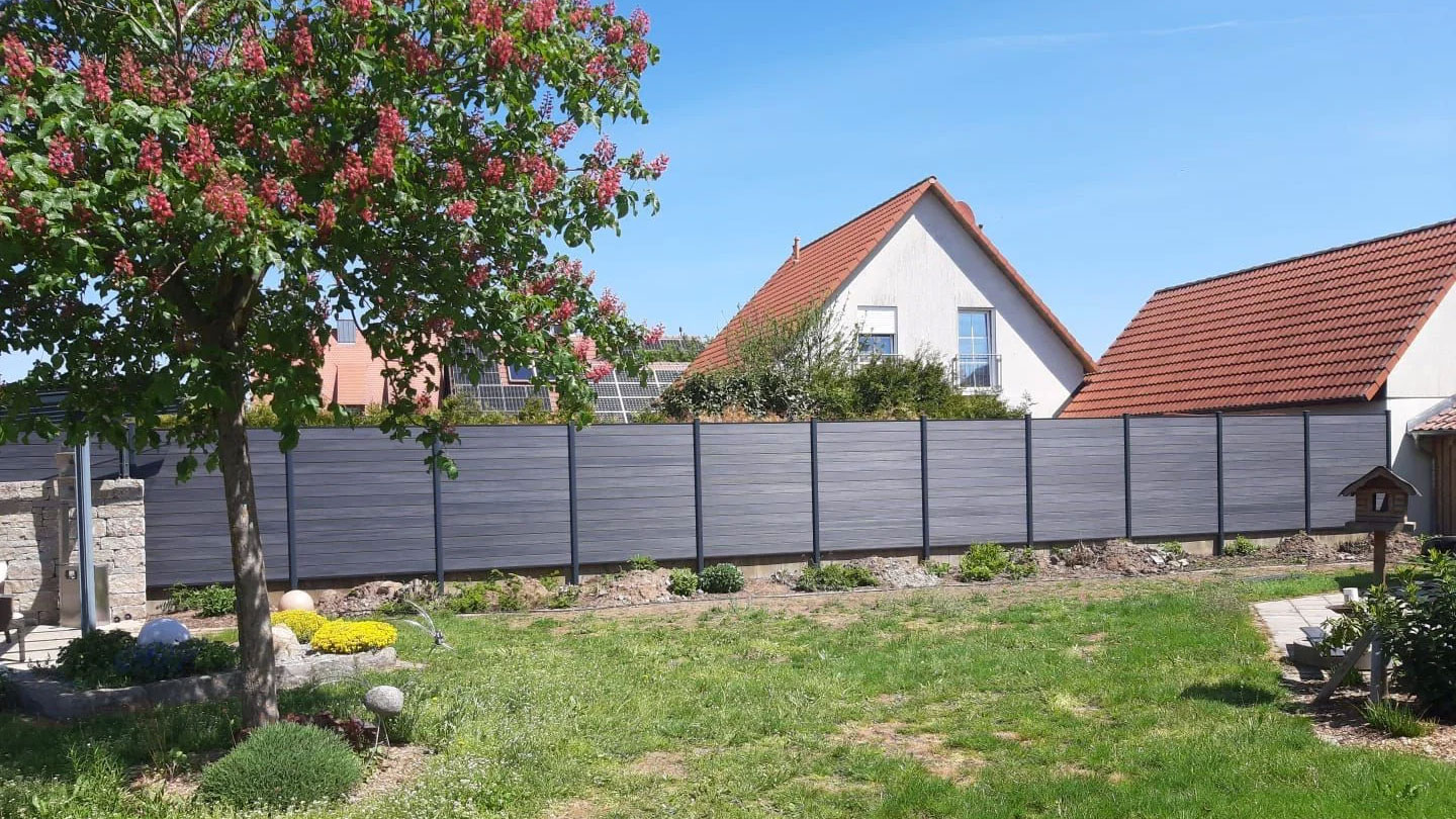 WPC Sichtschutzzaun in Anthrazit mit waagerechten Lamellen als Grundstücksgrenze in einem Garten
